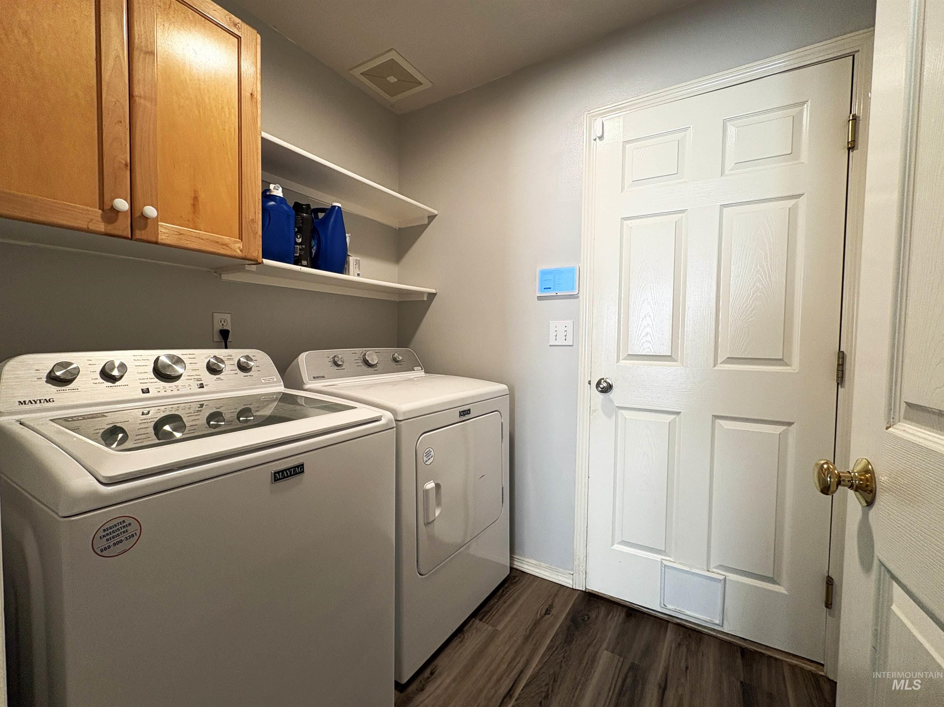 Laundry area with dark wood-style flooring, cabinet space, and washer and dryer