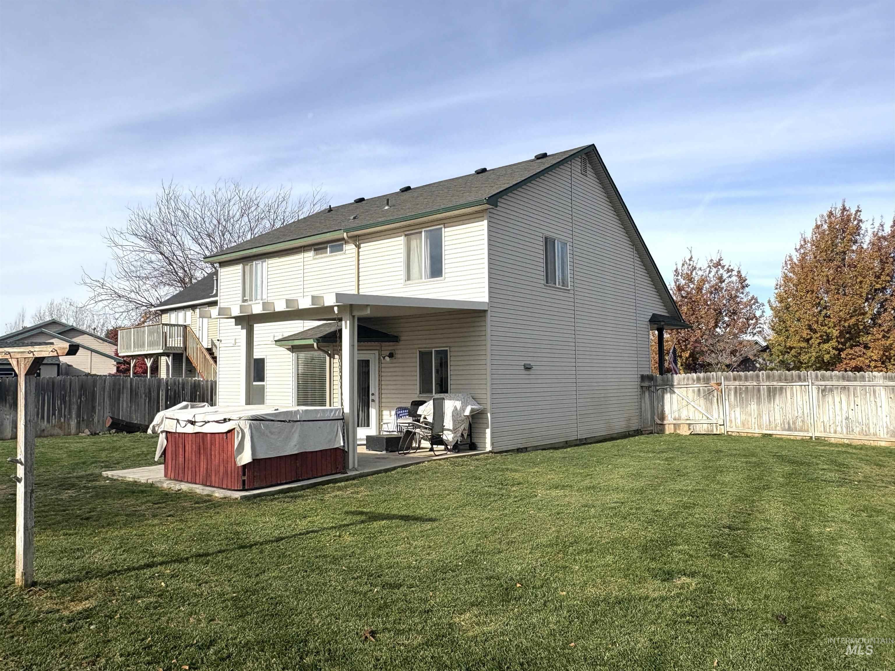 Back of property with a fenced backyard, a hot tub, and a patio area