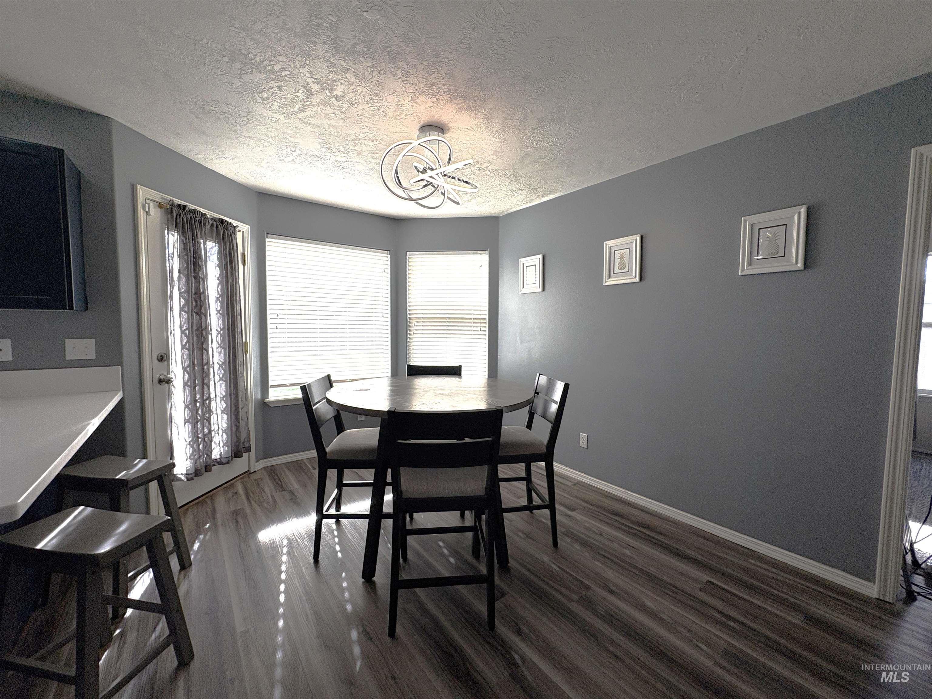 Dining space with dark wood finished floors, a textured ceiling, and healthy amount of natural light