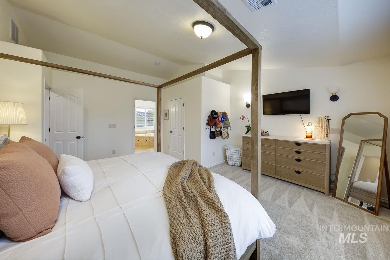 Bedroom featuring light colored carpet and connected bathroom