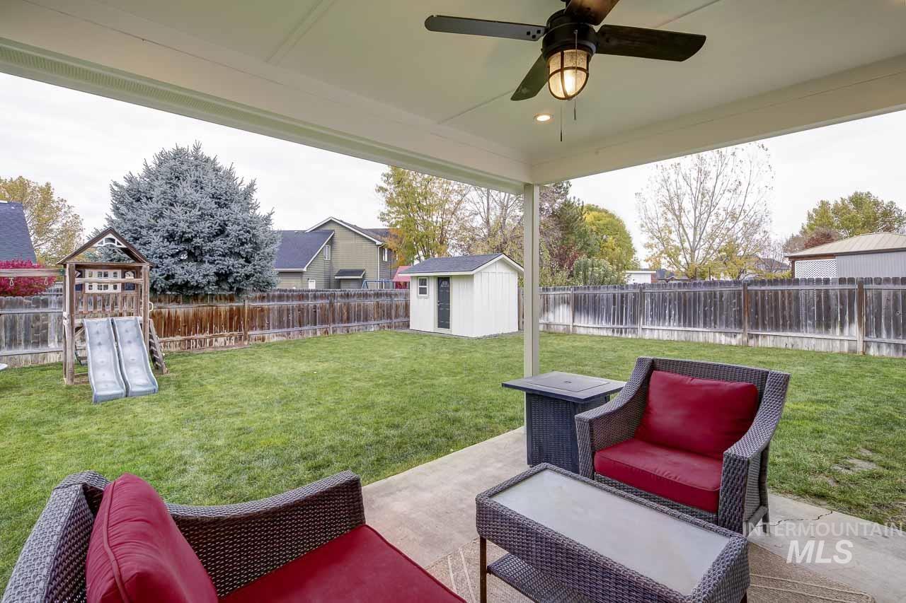 Fenced backyard with a patio, a ceiling fan, a storage shed, and a playground