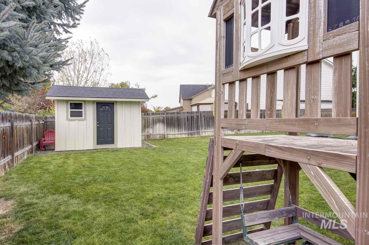 Fenced backyard featuring a storage unit