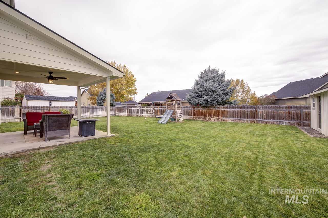 Fenced backyard featuring a patio area, a playground, and ceiling fan