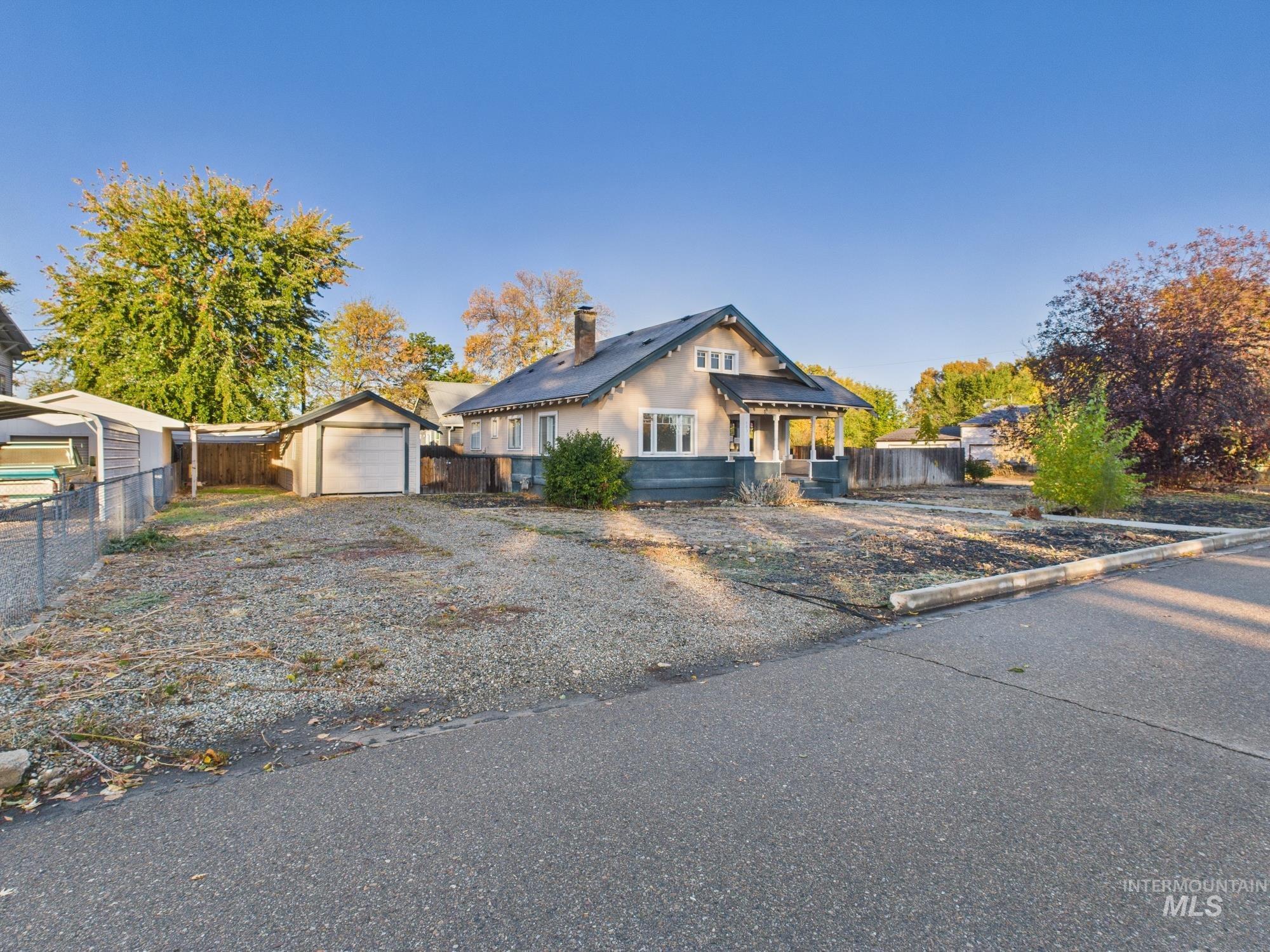 View of front facade with an outdoor structure, a chimney, driveway, and a detached garage