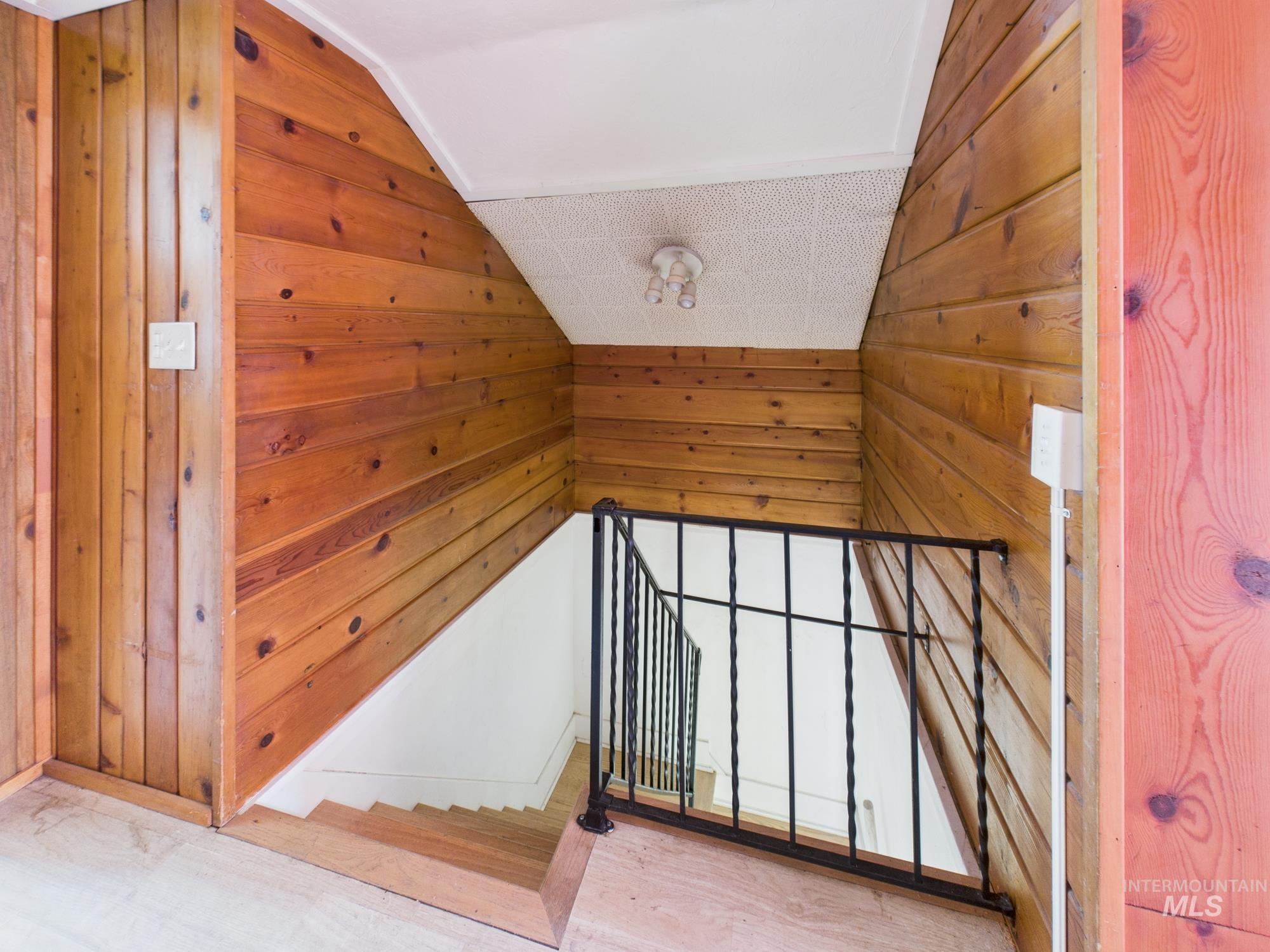 Stairs featuring lofted ceiling, wooden walls, and wood finished floors