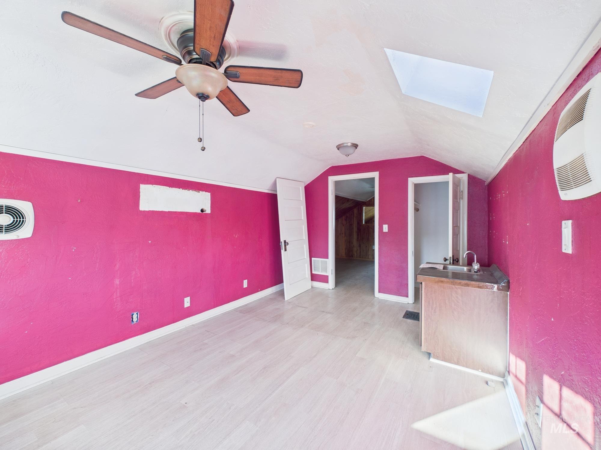 Bonus room featuring a skylight, vaulted ceiling, light wood-type flooring, and ceiling fan