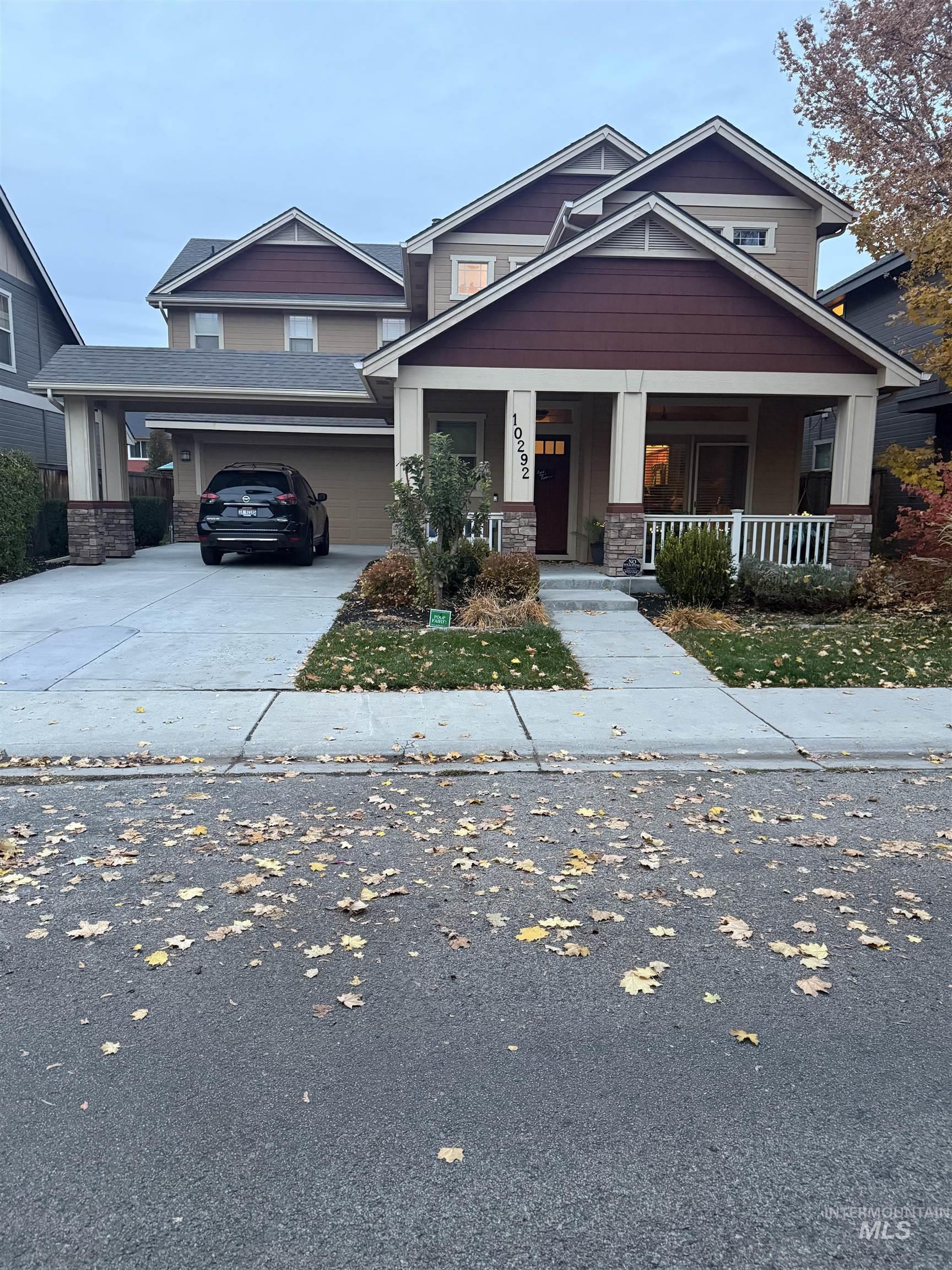 Craftsman-style house with covered porch, driveway, and stone siding
