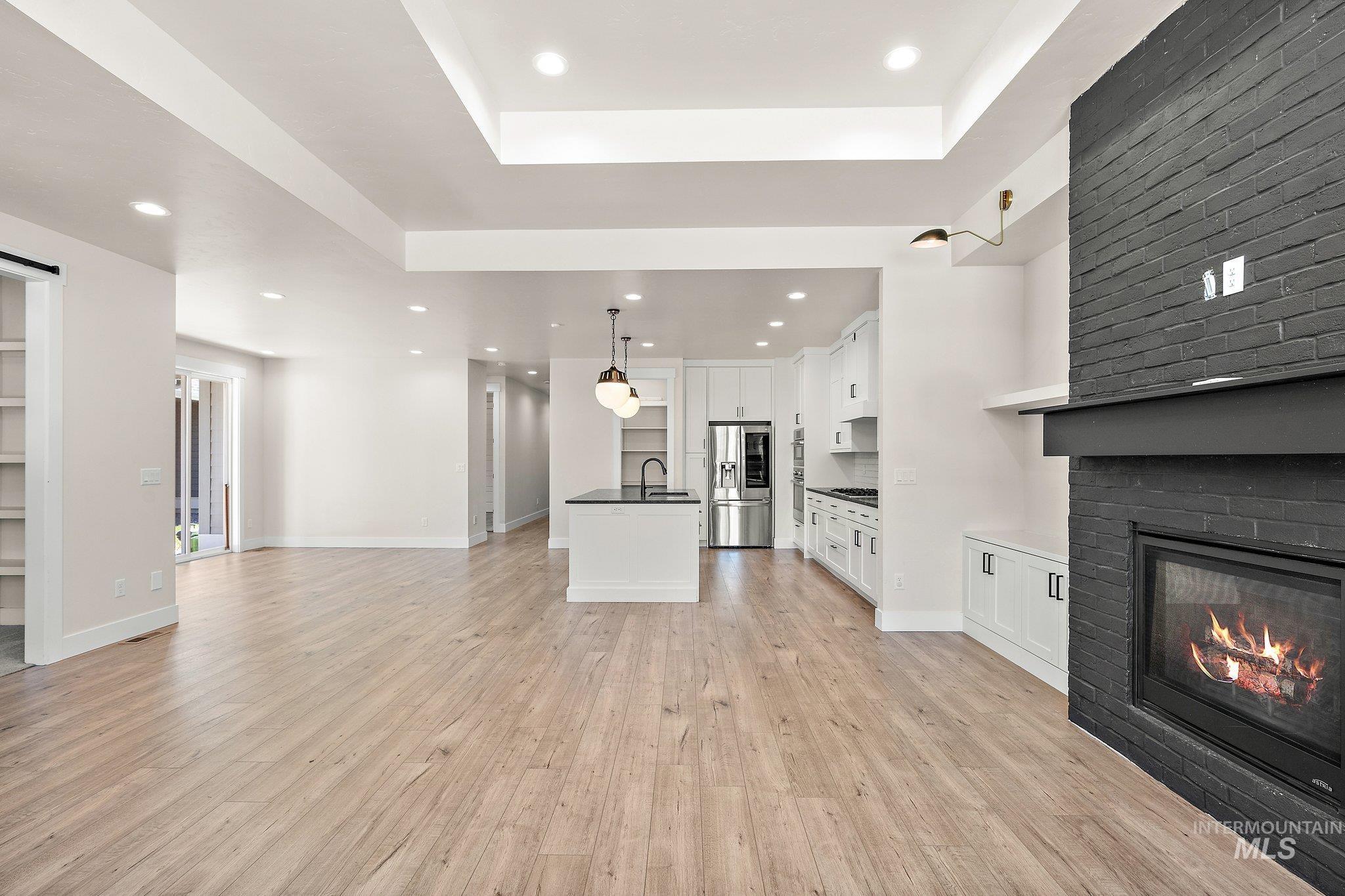 Unfurnished living room with recessed lighting, a raised ceiling, light wood finished floors, and a fireplace