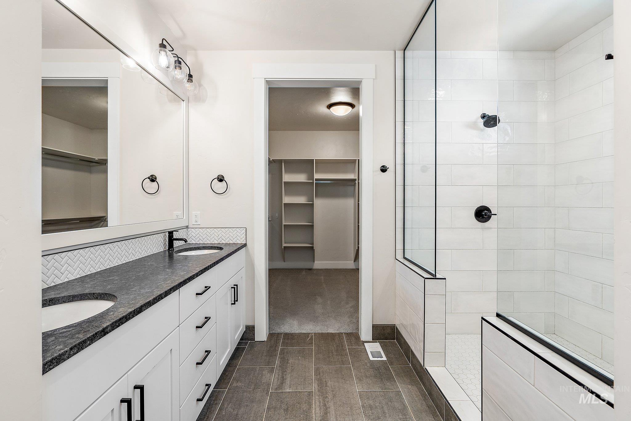 Full bathroom featuring a spacious closet, double vanity, and a walk in shower