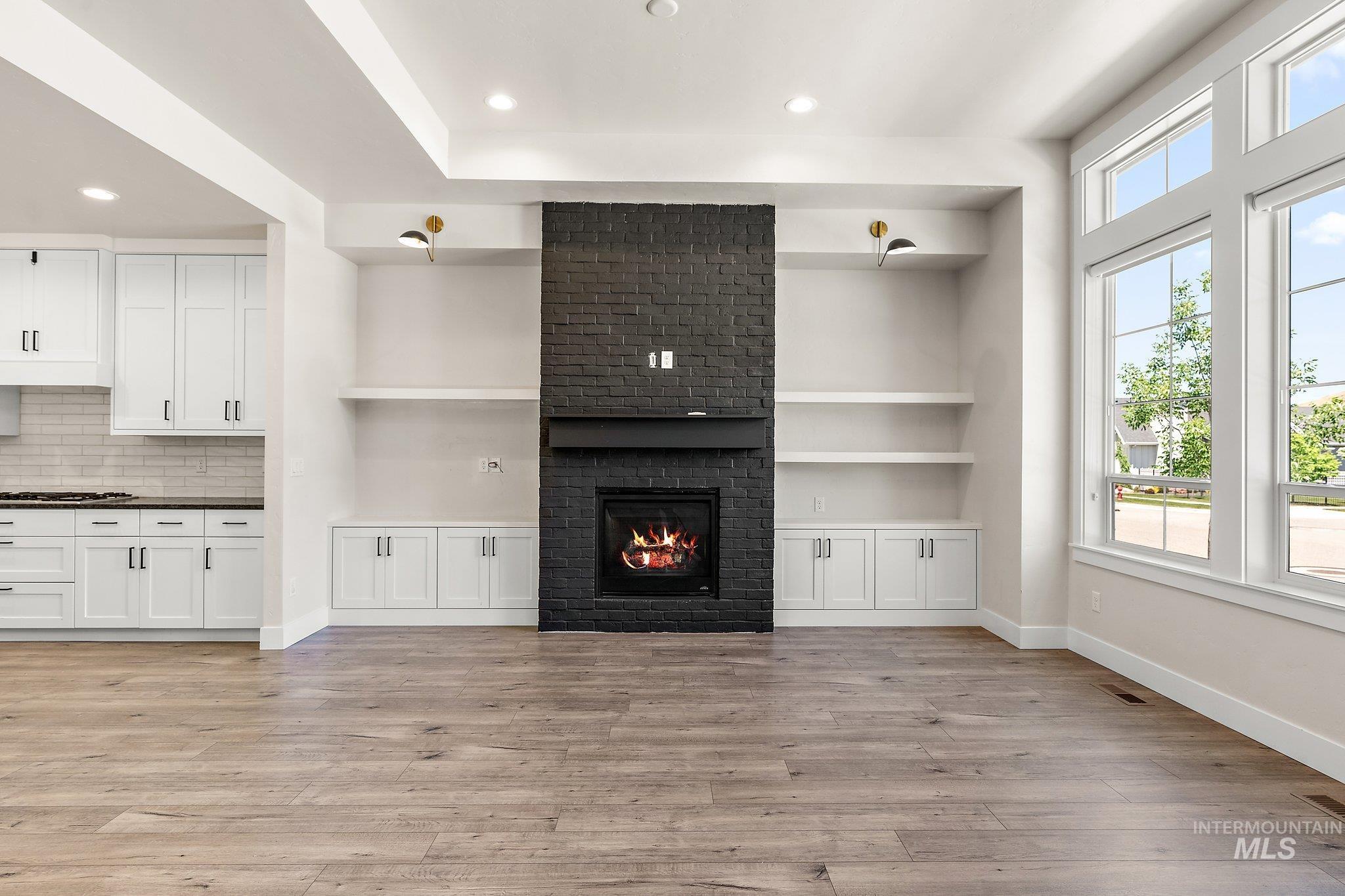 Unfurnished living room with a fireplace, light wood-type flooring, recessed lighting, and built in features