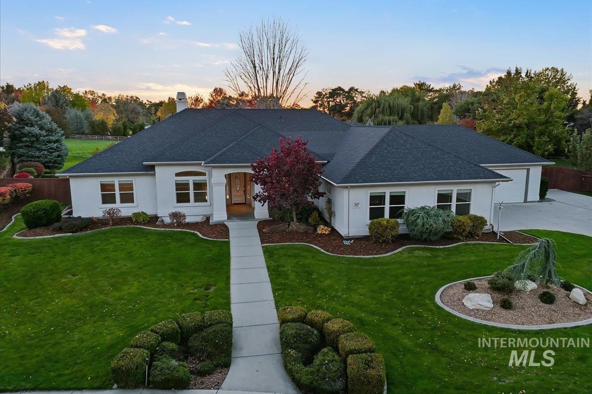 Ranch-style home featuring a garage, a shingled roof, a chimney, and stucco siding