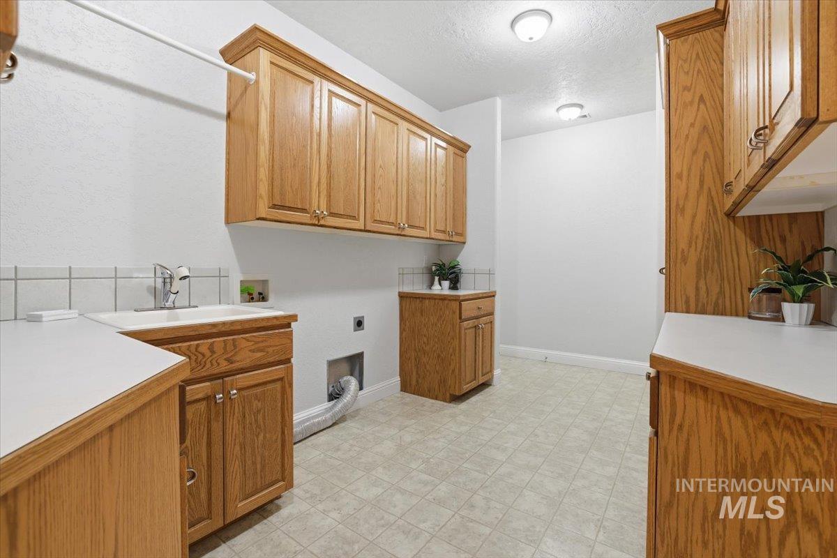 Laundry area featuring cabinet space, a textured ceiling, washer hookup, electric dryer hookup, and light flooring