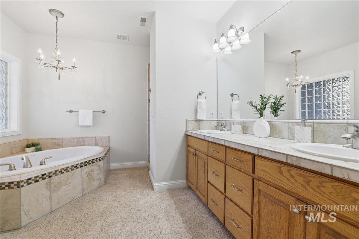 Bathroom with a chandelier, double vanity, and a bath
