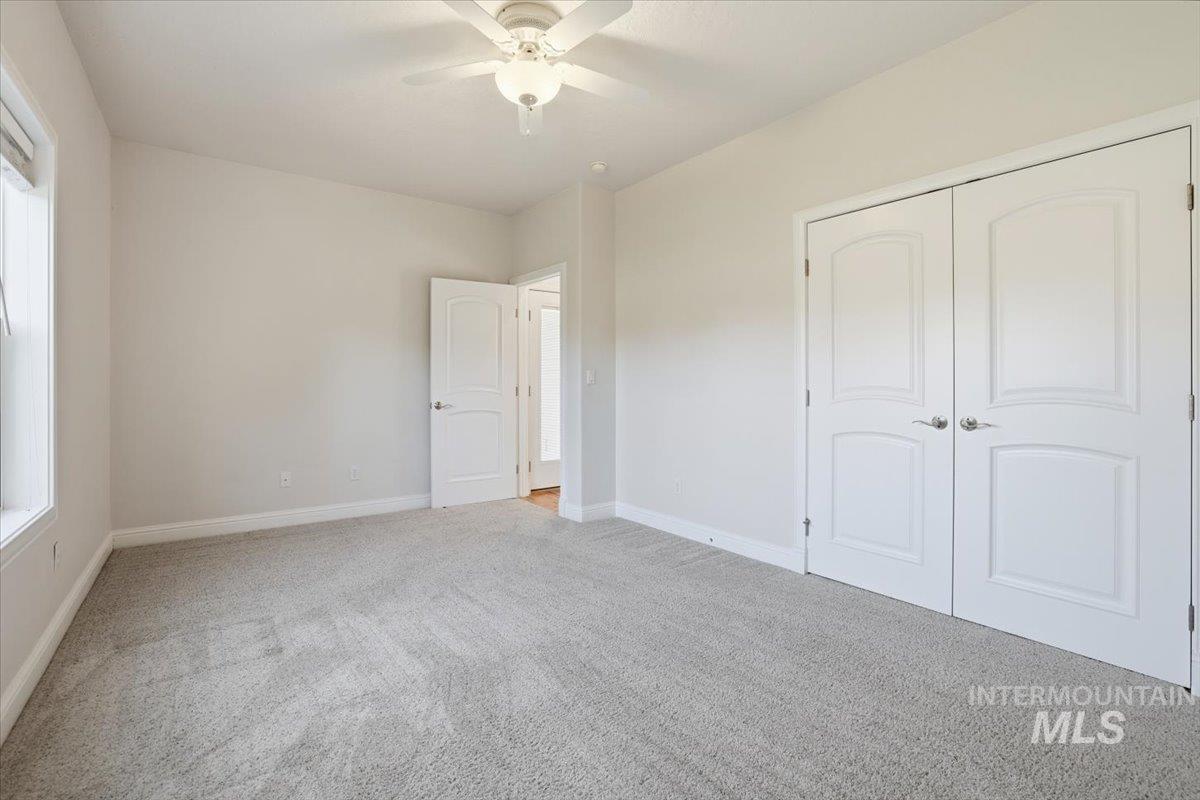 Unfurnished bedroom featuring light carpet, ceiling fan, and a closet
