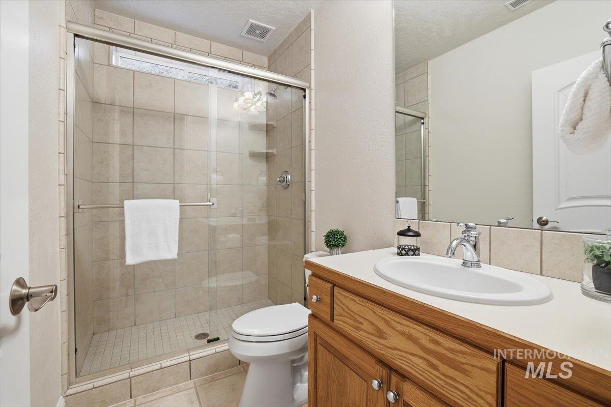 Bathroom with vanity, a stall shower, a textured ceiling, and tile patterned flooring