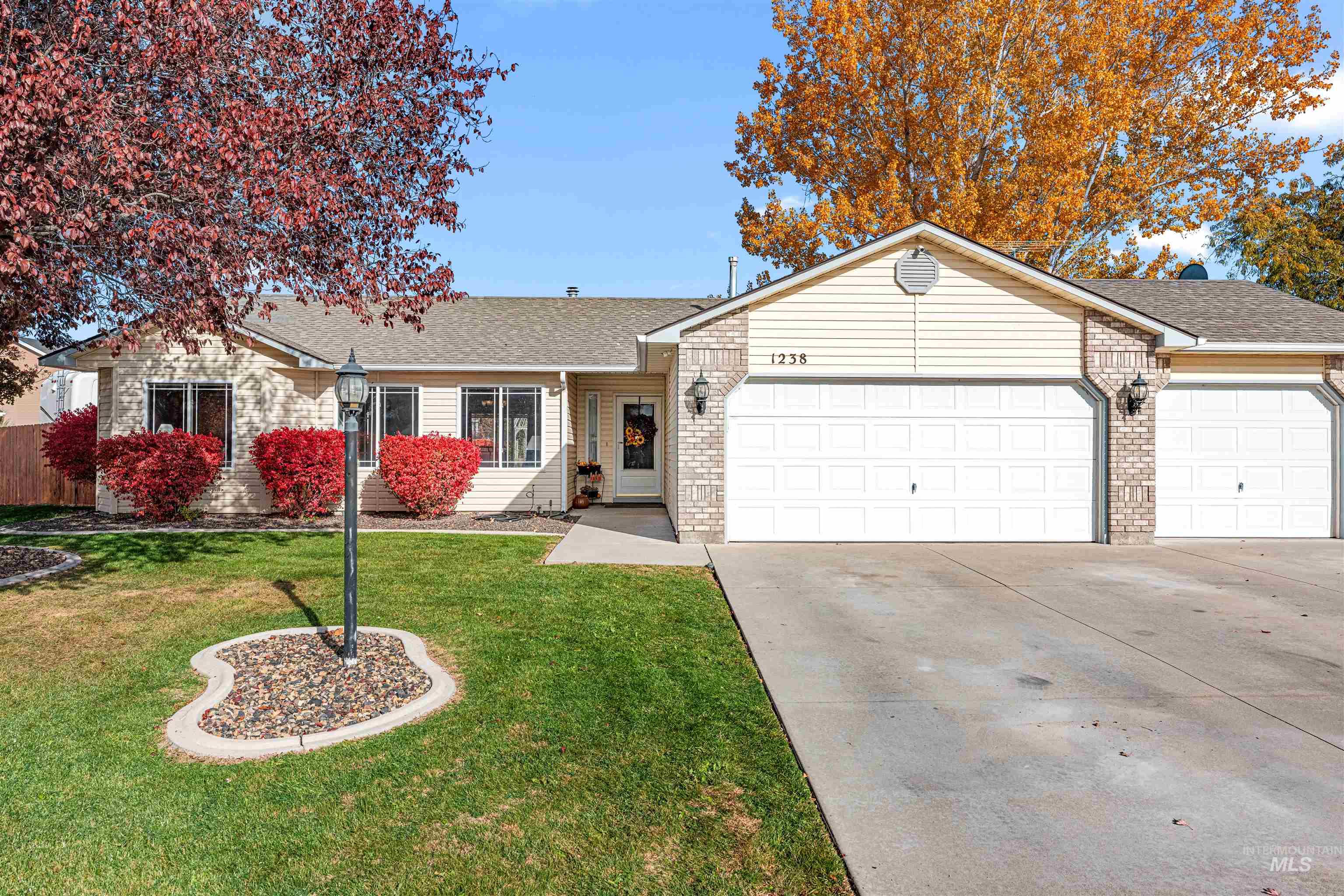Ranch-style home featuring roof with shingles, driveway, a front yard, an attached garage, and brick siding