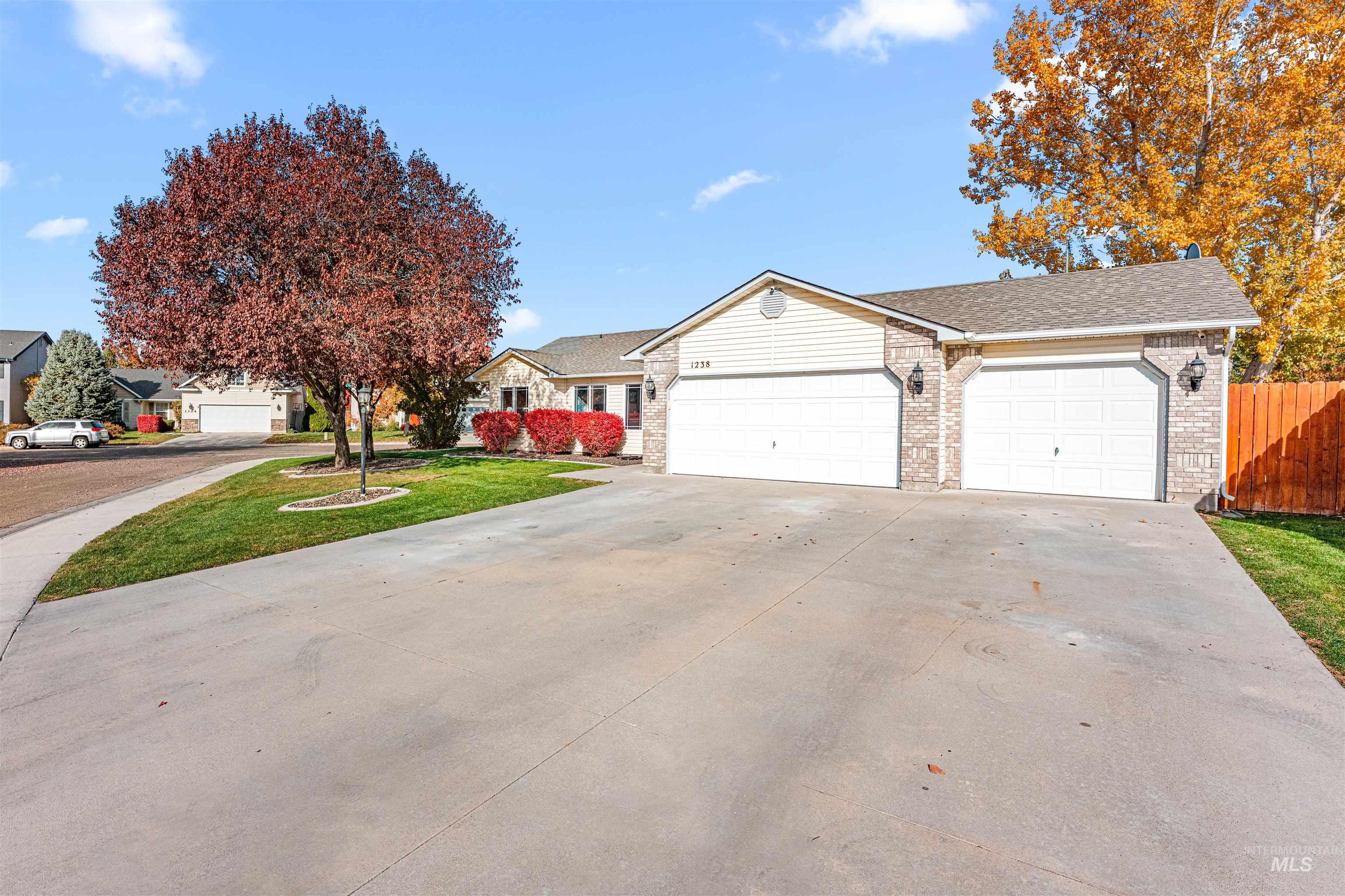 View of front facade featuring driveway, brick siding, a shingled roof, and a garage