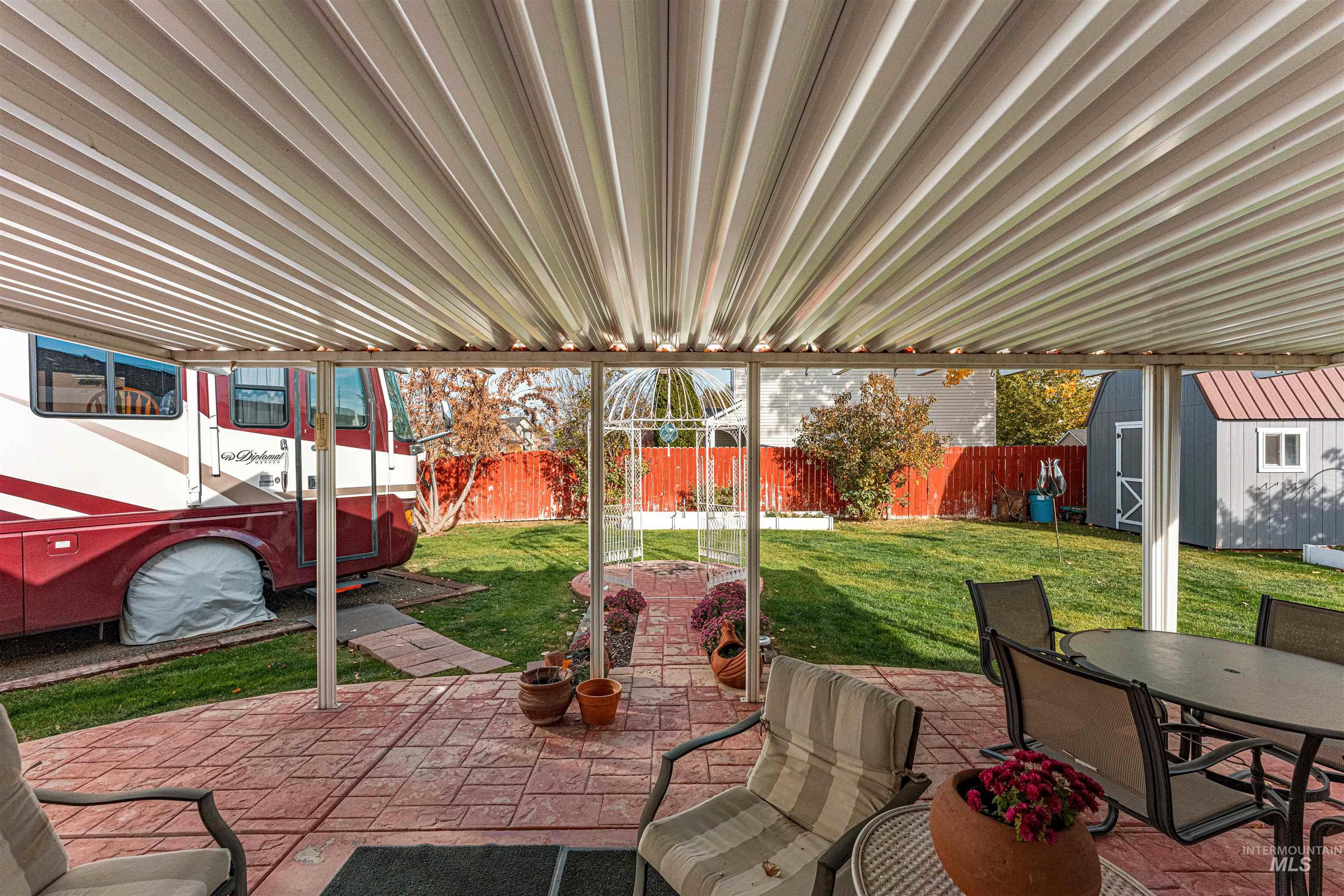 Fenced backyard with a storage unit, outdoor dining area, and a patio area