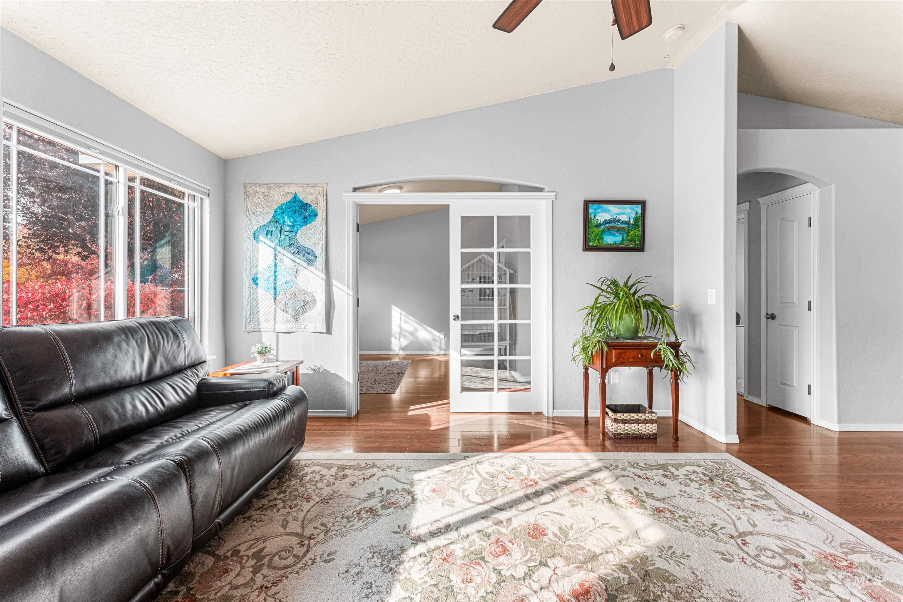 Sitting room featuring arched walkways, vaulted ceiling, a ceiling fan, wood finished floors, and french doors
