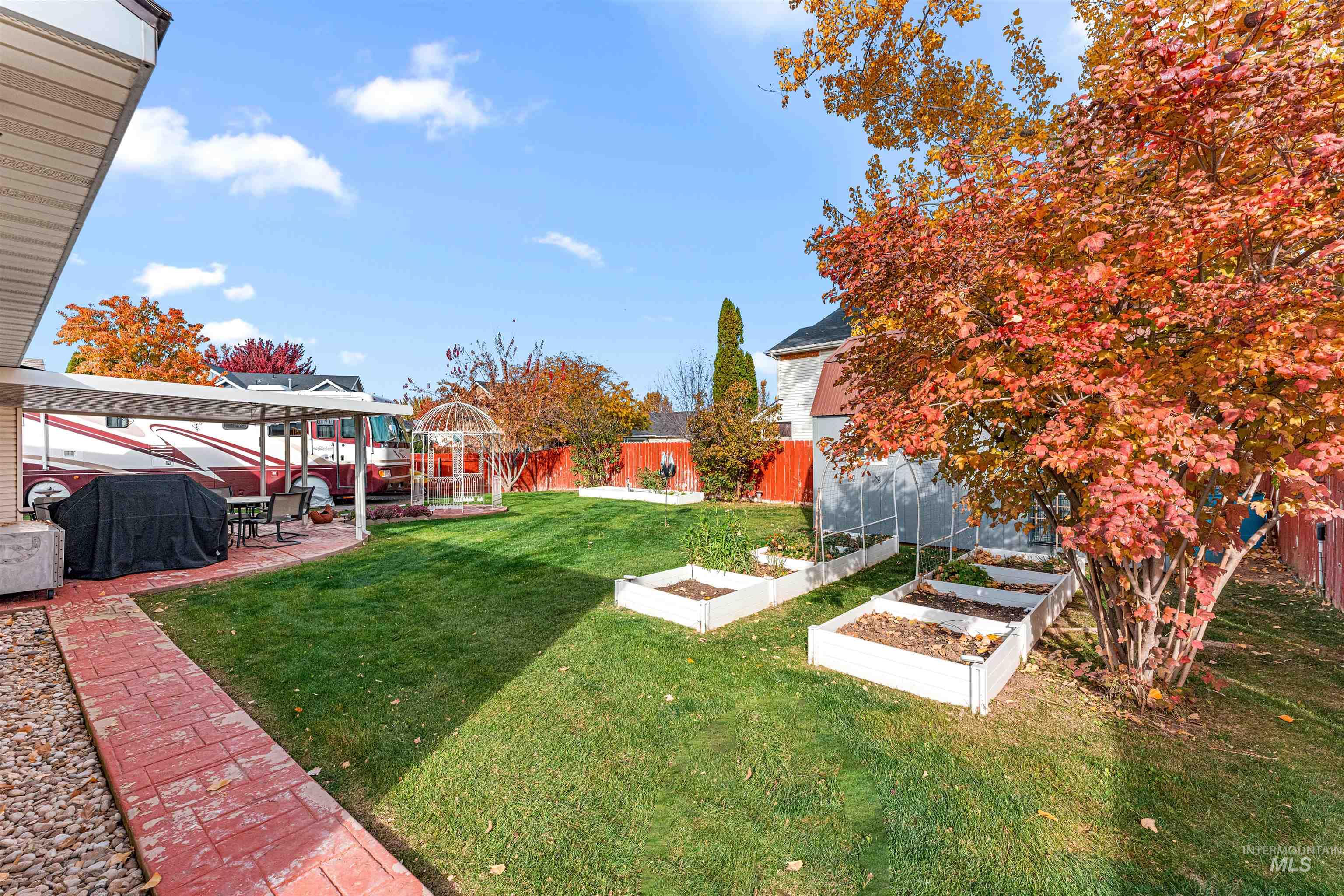 Fenced backyard with a vegetable garden and a patio area