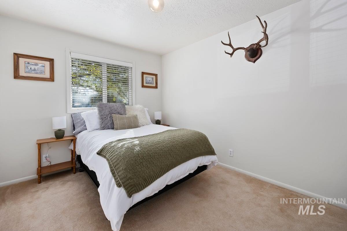 Carpeted bedroom featuring a textured ceiling and baseboards