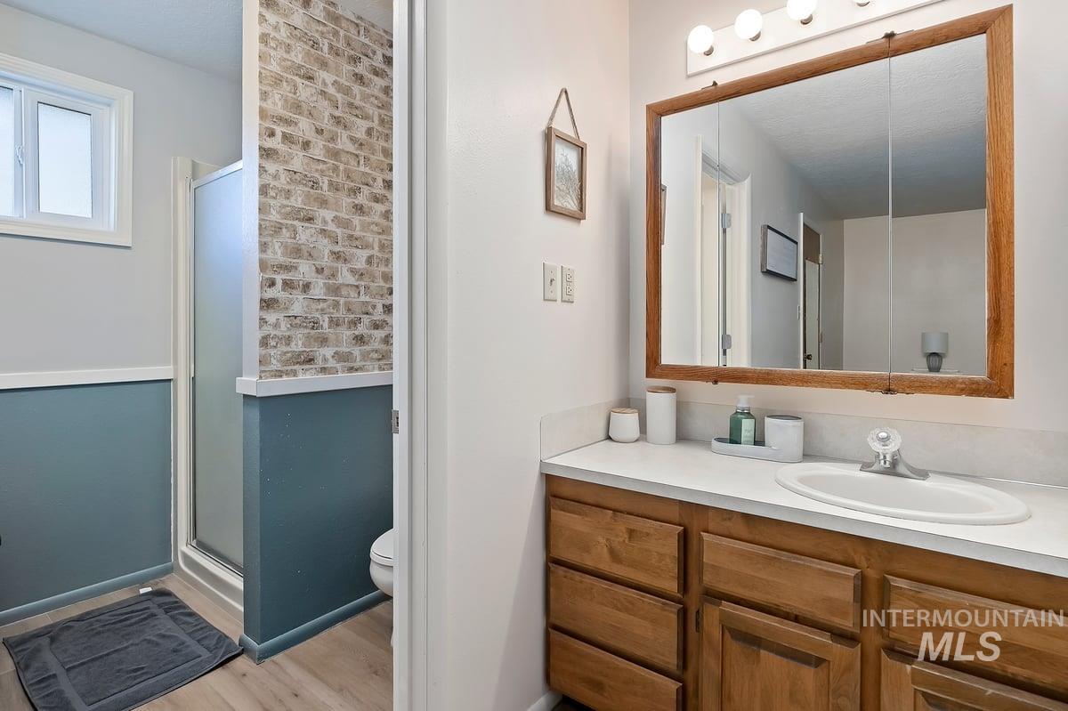 Full bath with vanity, a shower stall, and light wood-type flooring