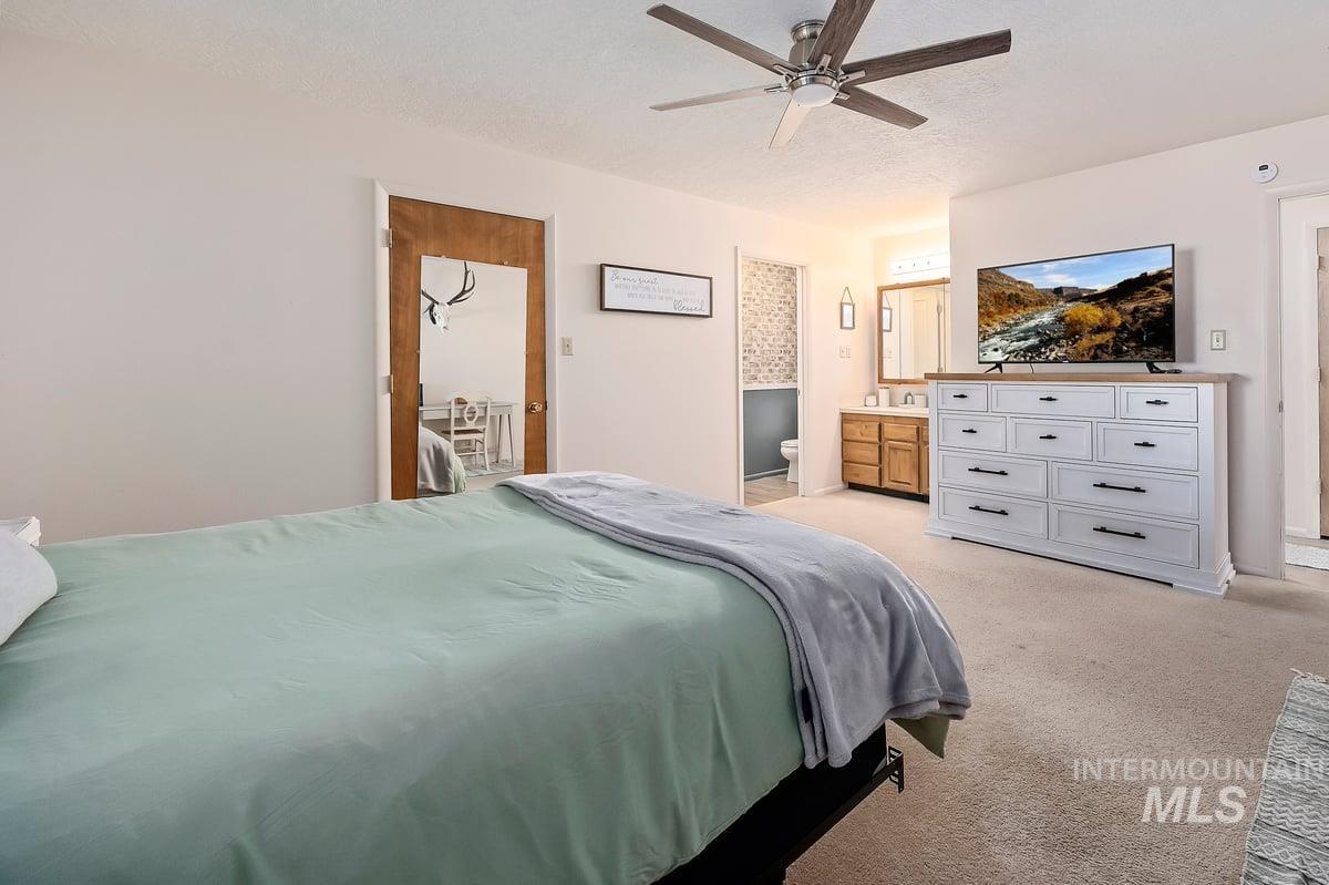 Bedroom featuring light carpet, a ceiling fan, a textured ceiling, and ensuite bathroom