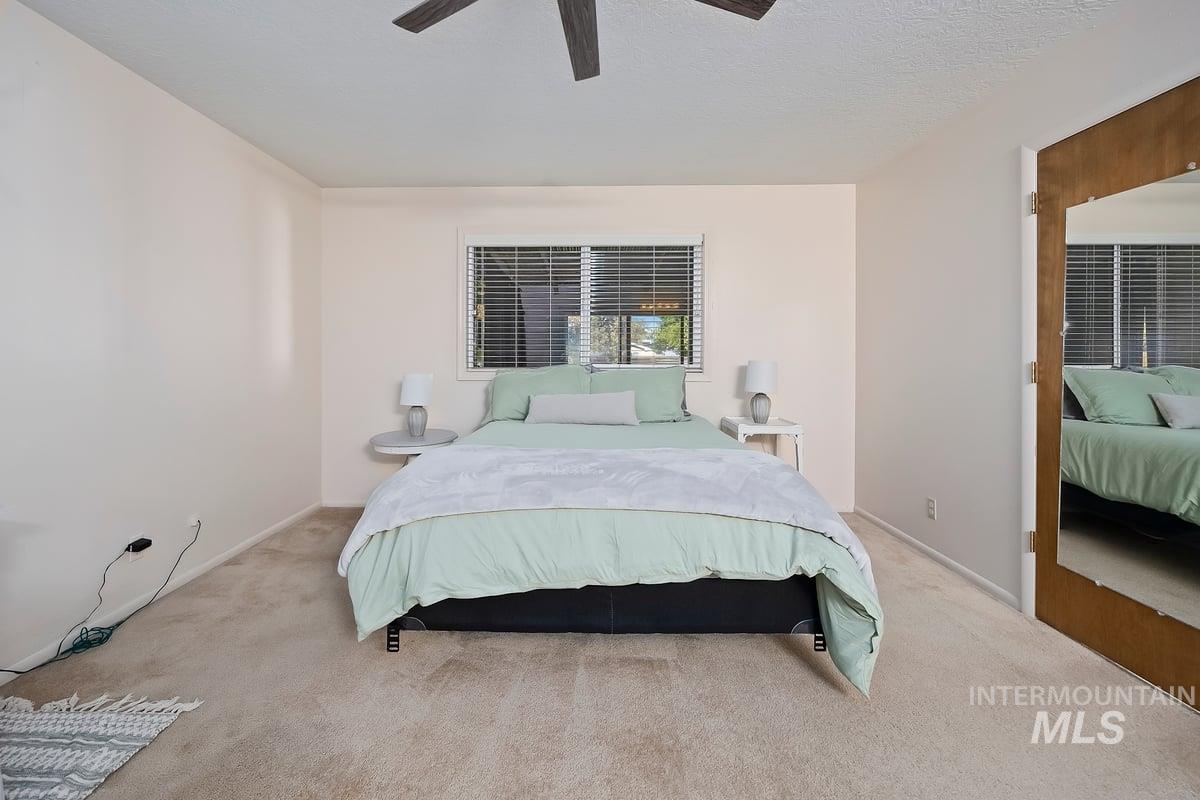 Carpeted bedroom with a ceiling fan and a textured ceiling