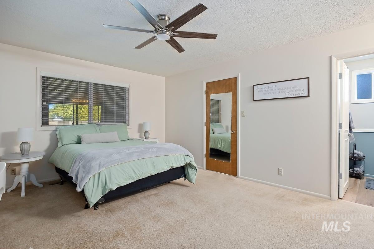 Bedroom with carpet flooring, a ceiling fan, and a textured ceiling