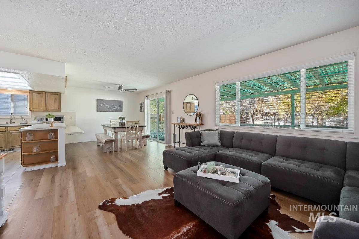 Living area featuring a textured ceiling, light wood finished floors, and ceiling fan