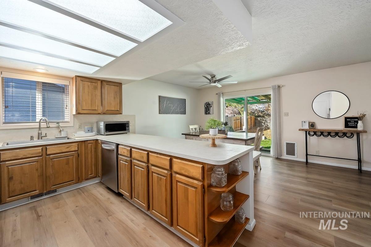Kitchen featuring brown cabinetry, a peninsula, light countertops, open shelves, and a textured ceiling