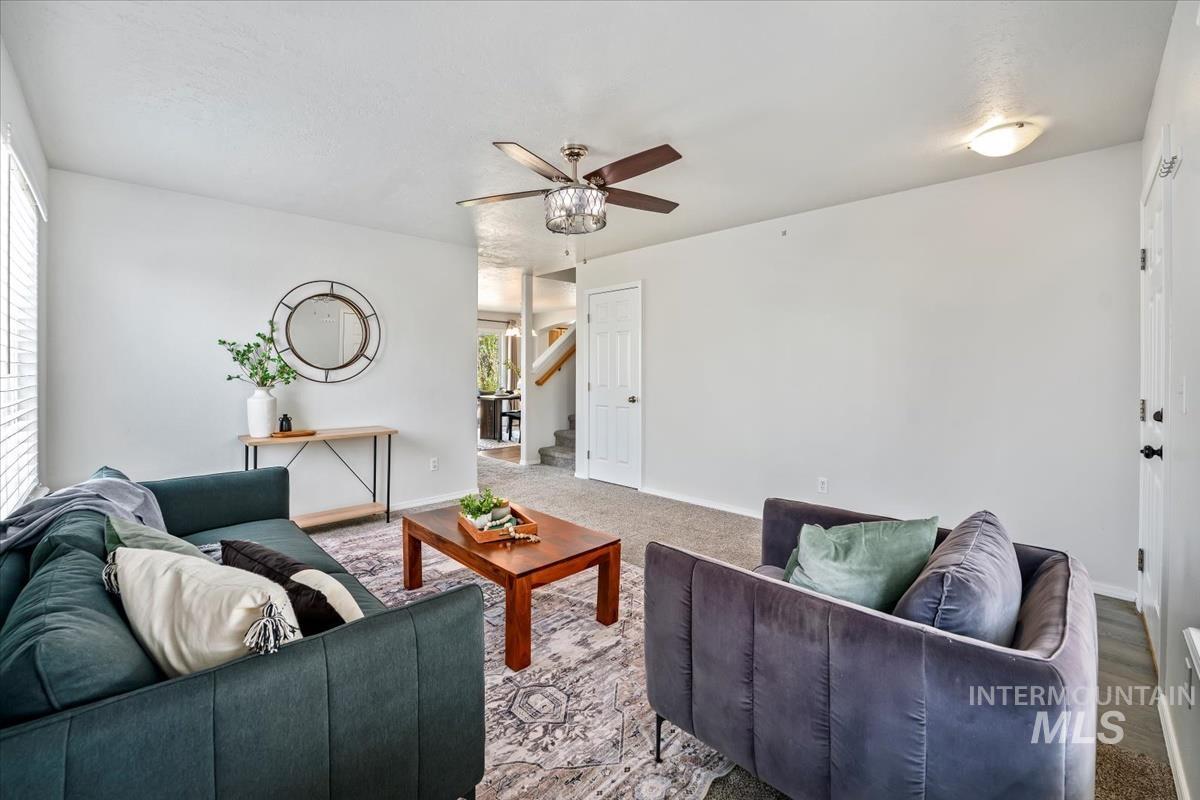 Living room featuring stairs, ceiling fan, and carpet floors
