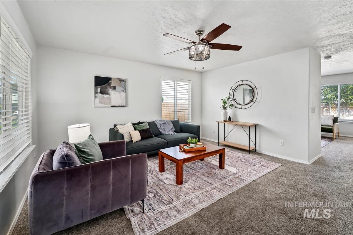 Living area featuring carpet flooring, a ceiling fan, and a textured ceiling