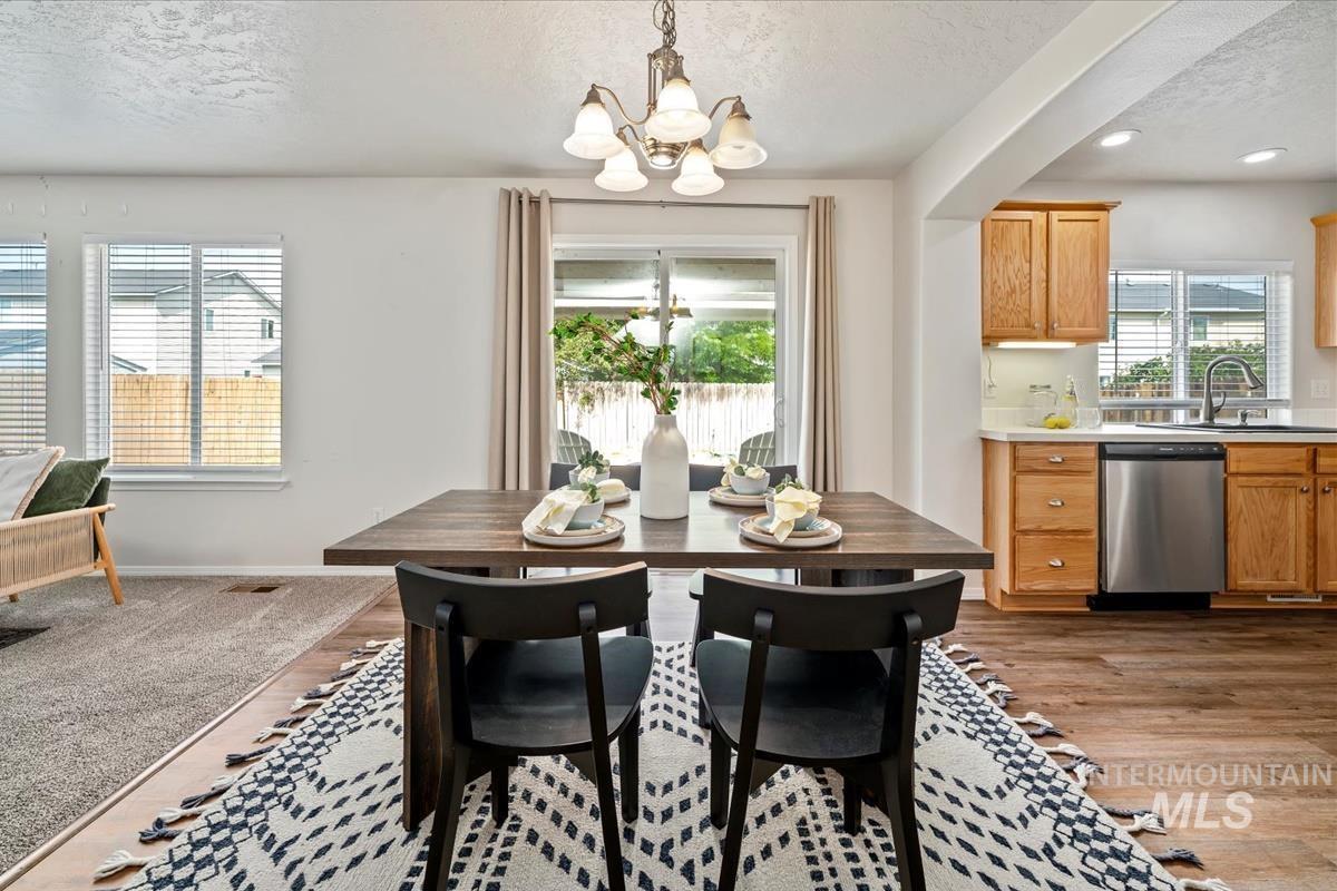 Dining area featuring a textured ceiling, a chandelier, light wood-style flooring, and recessed lighting