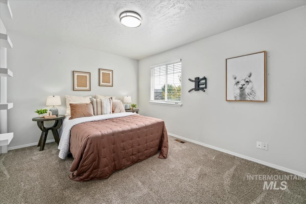 Carpeted bedroom featuring a textured ceiling and baseboards