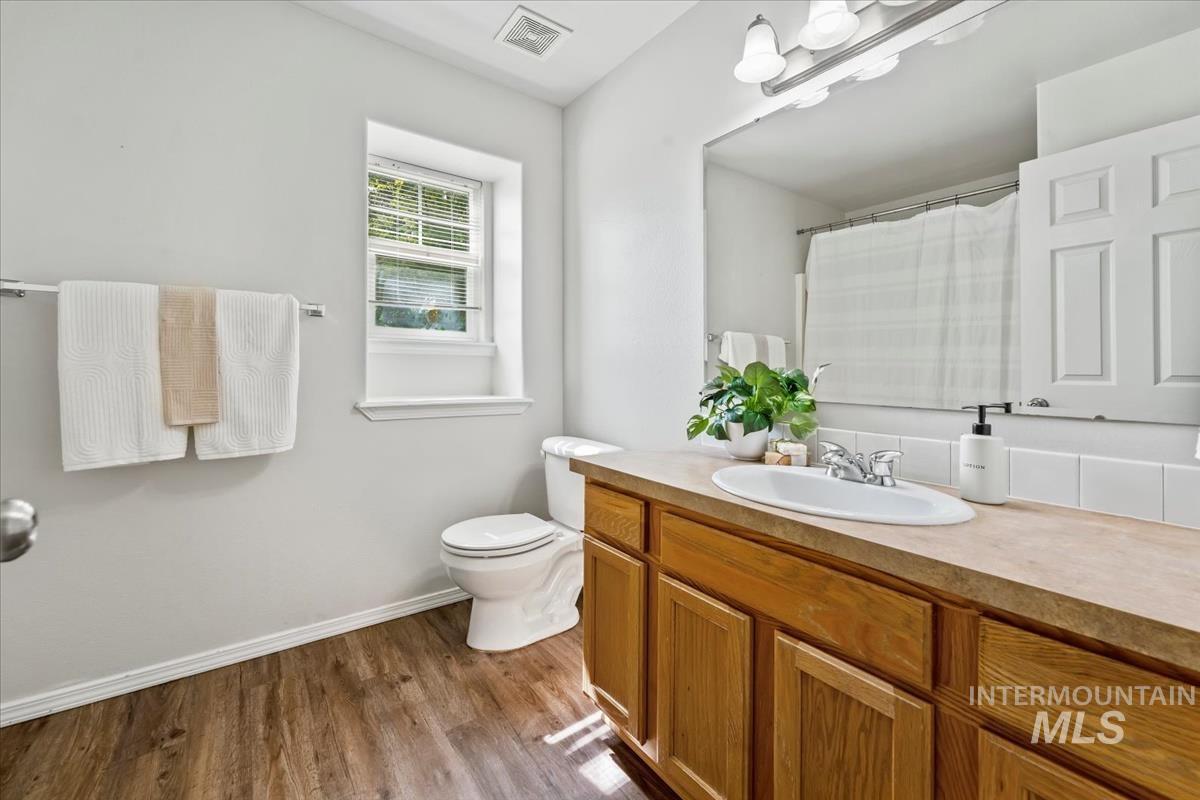 Full bath featuring a shower with curtain, vanity, and dark wood-style floors