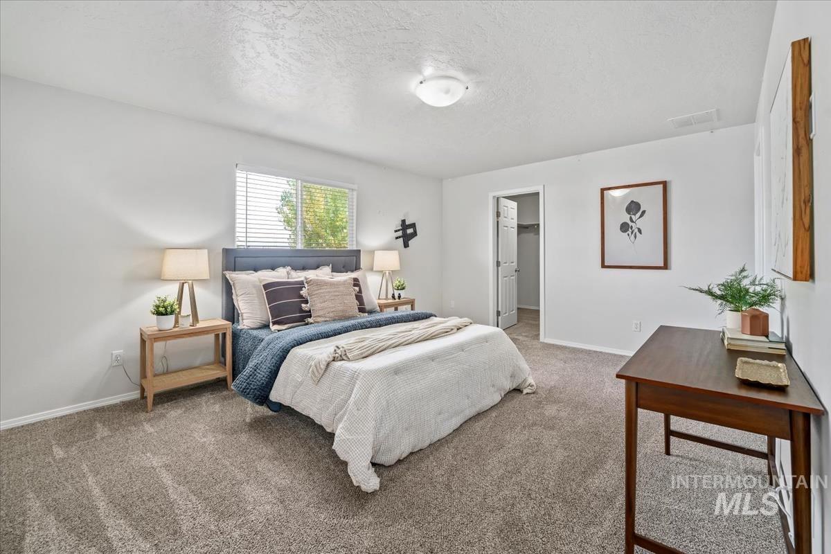 Carpeted bedroom with a walk in closet and a textured ceiling