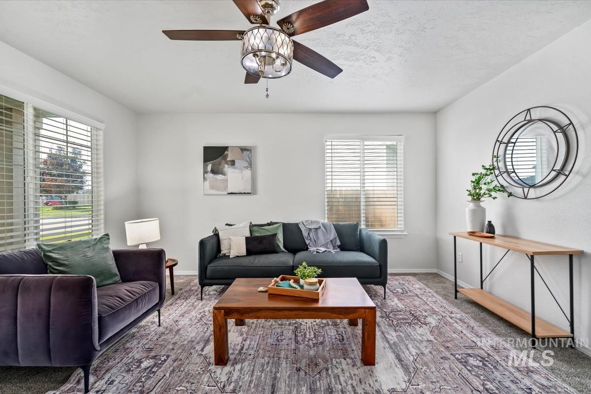 Living area with carpet, a ceiling fan, and a textured ceiling