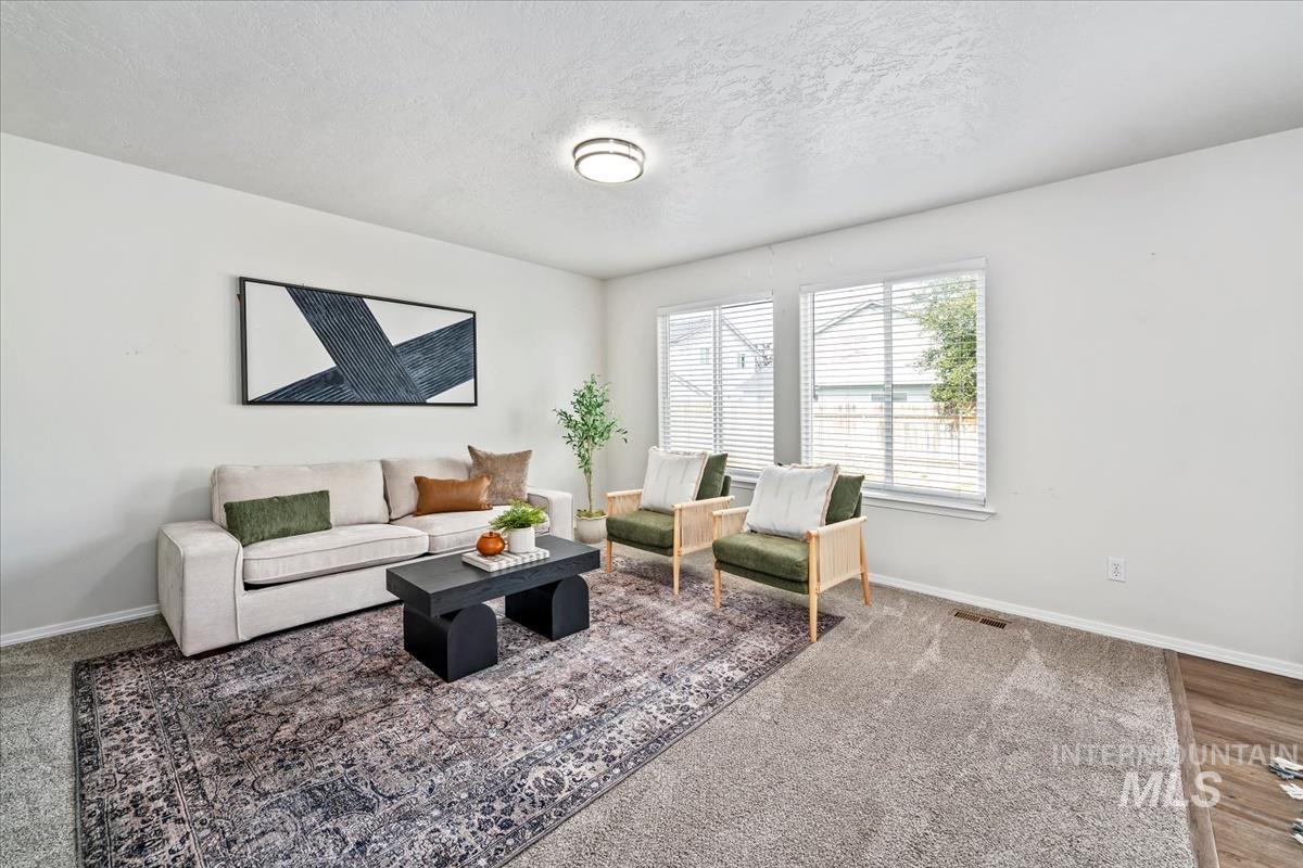 Carpeted living room featuring a textured ceiling and baseboards