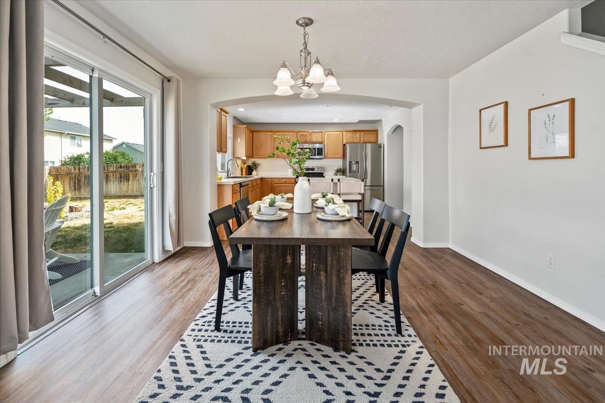 Dining area featuring a chandelier, arched walkways, and light wood-style flooring