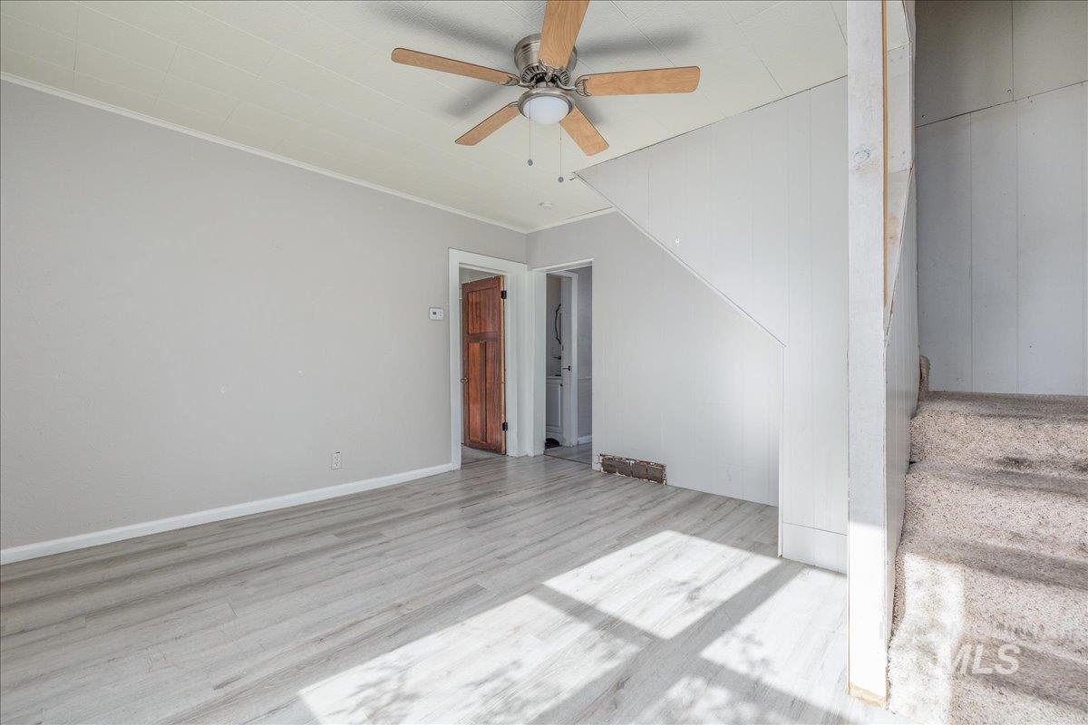 Spare room featuring light wood finished floors, crown molding, and a ceiling fan