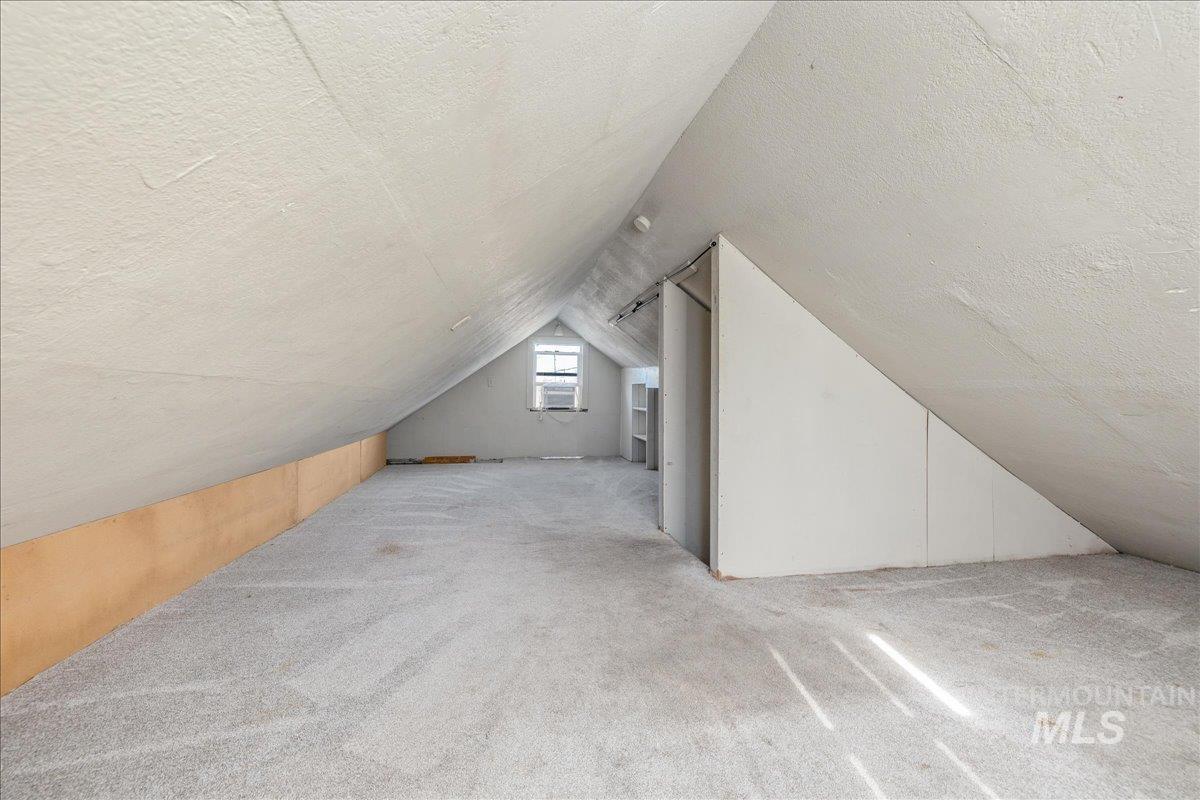 Bonus room featuring a textured ceiling, carpet, and lofted ceiling