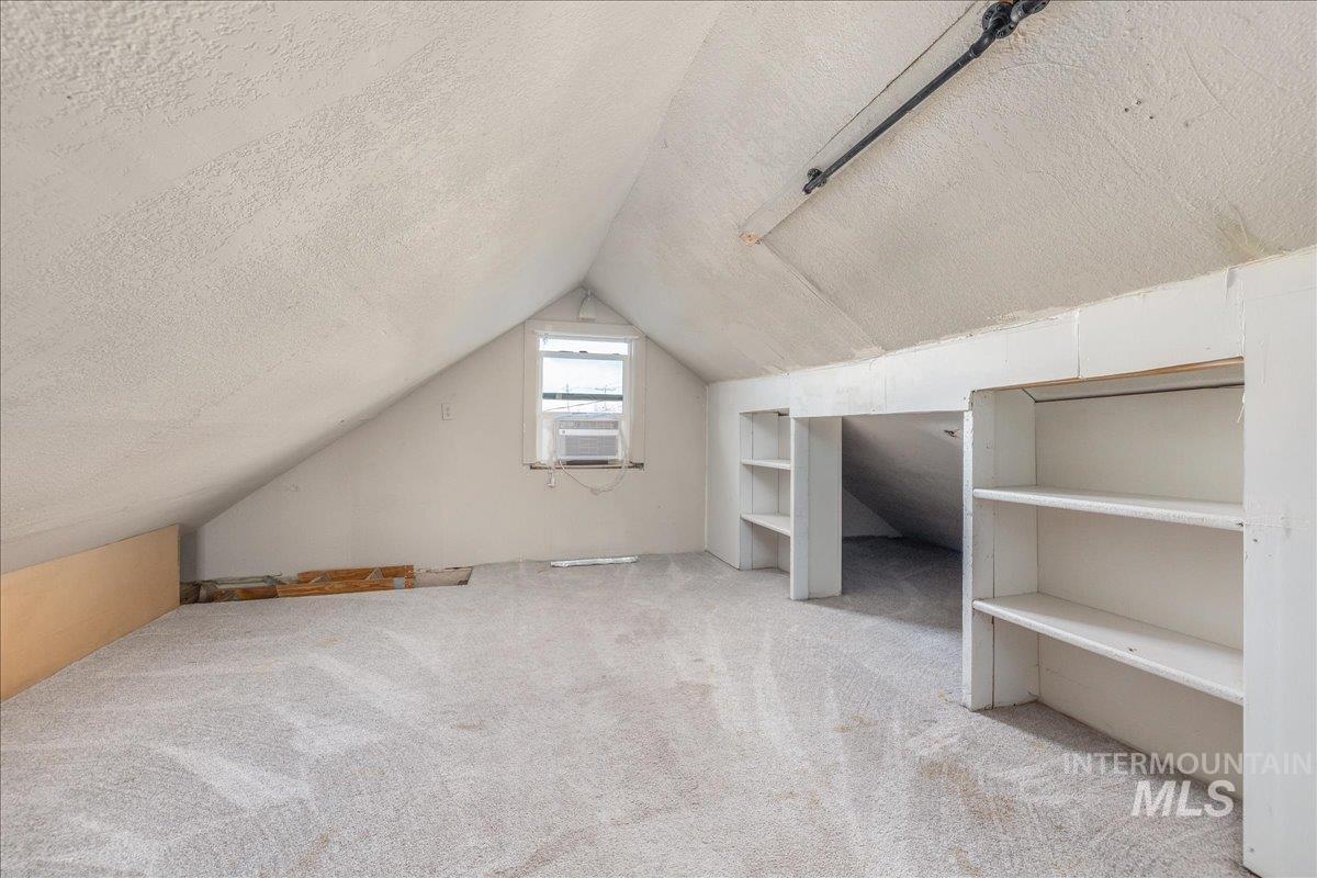 Bonus room featuring a textured ceiling, light carpet, lofted ceiling, and built in features