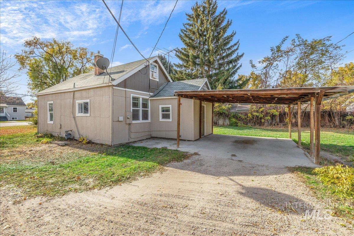 View of property exterior featuring a chimney, a yard, roof with shingles, and dirt driveway