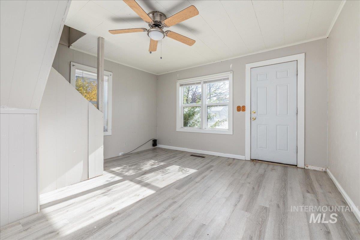 Entrance foyer with ornamental molding, light wood-style flooring, and a ceiling fan