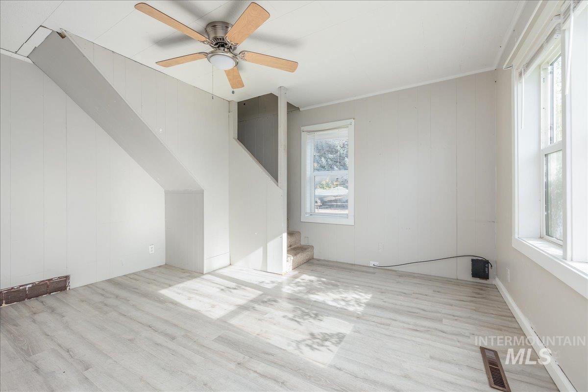 Additional living space featuring plenty of natural light, wood finished floors, stairway, wood walls, and ceiling fan