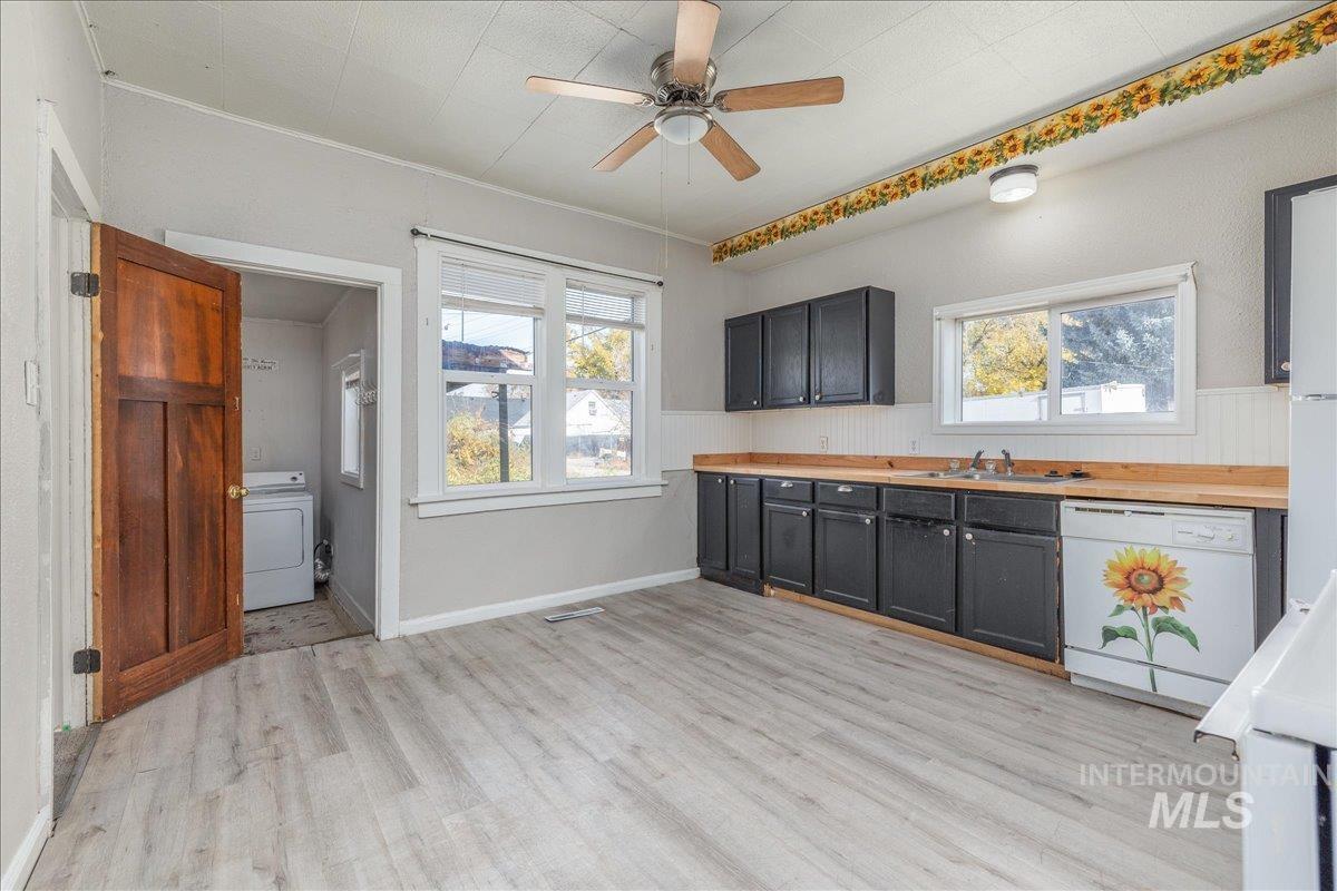 Kitchen featuring light countertops, dishwasher, light wood-style flooring, washer / clothes dryer, and plenty of natural light