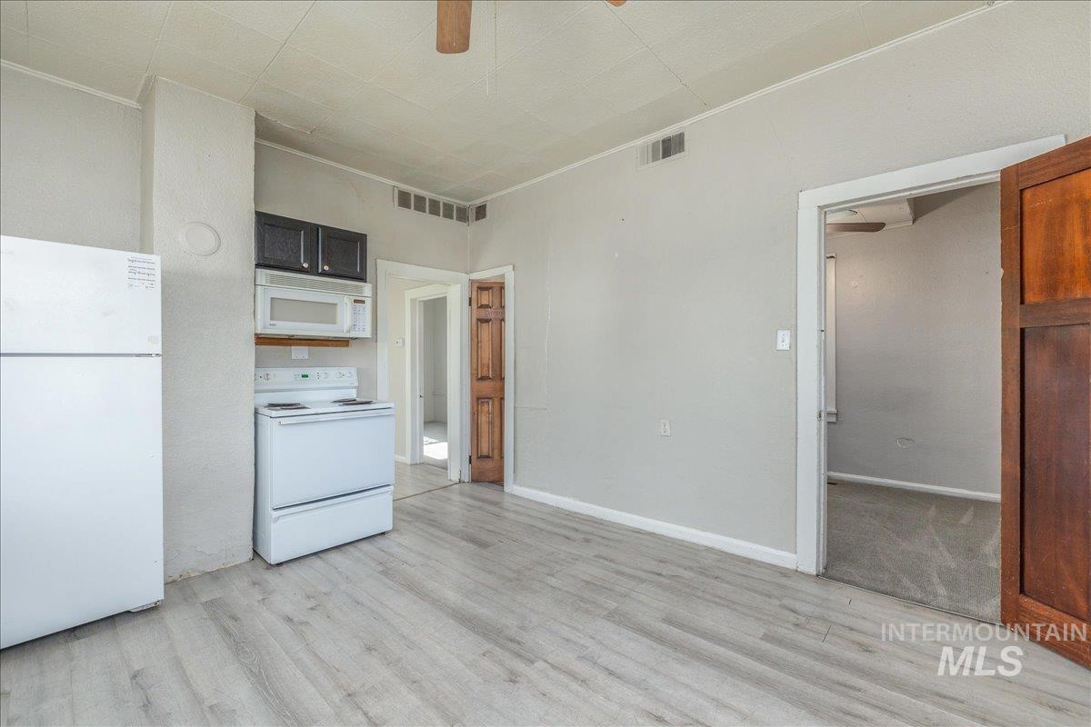 Kitchen featuring white appliances, ceiling fan, ornamental molding, and light wood-type flooring