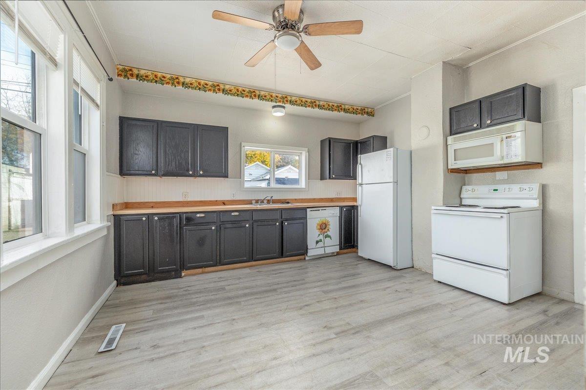 Kitchen featuring white appliances, light countertops, light wood-style floors, ornamental molding, and ceiling fan