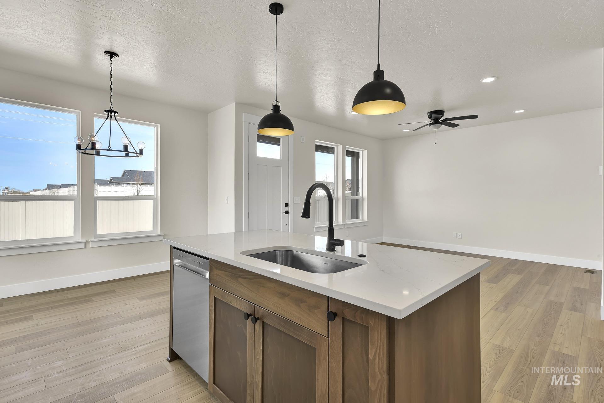 Kitchen featuring brown cabinetry, decorative light fixtures, light wood-style flooring, a textured ceiling, and recessed lighting